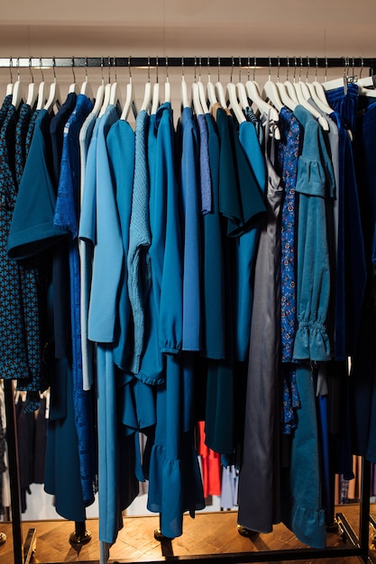 Close up view of various stylish clothes hanging on hangers in boutique