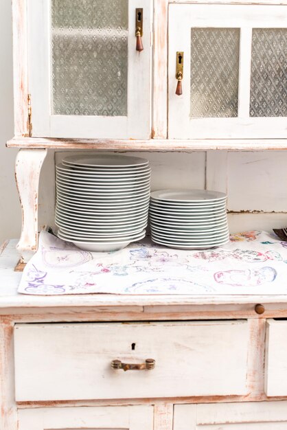 Close up view of vintage kitchen cupboard in cafe or at home. White plates standing at each other. Stock photo
