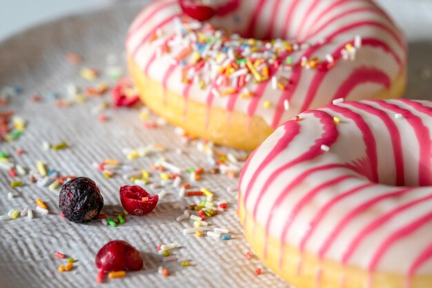 Photo close up view of white pink frosted donuts on the plate