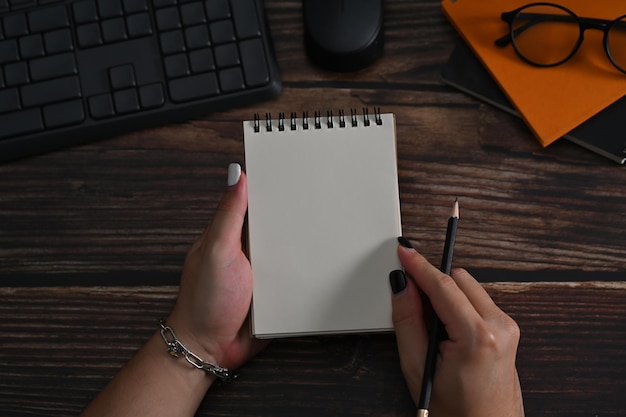 Close up view woman hand holding pencil and empty notebook