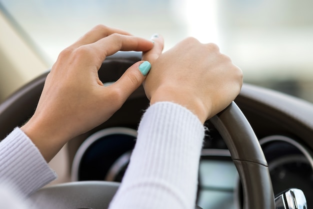 Vista ravvicinata della donna che tiene il volante alla guida di un'auto sulla strada della città in una giornata di sole.