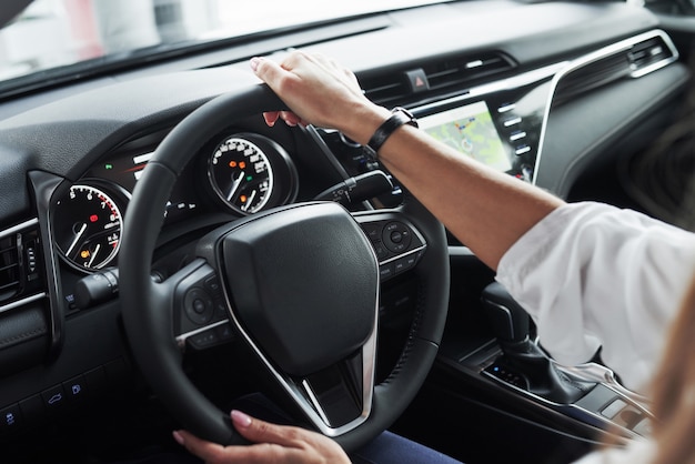 Close up view of woman's hands in the beautiful modern black colored car