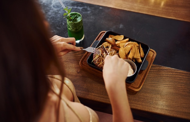 Close up view of woman that eats fast food indoors in the cafe.