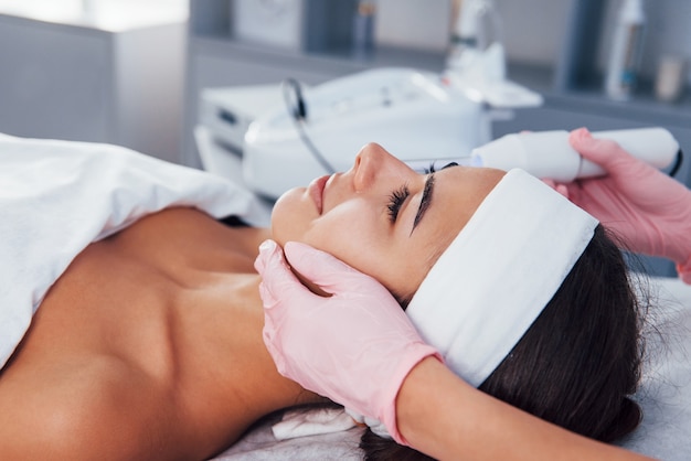 close up view of woman that lying down in spa salon and have face cleaning procedure by using modern device.
