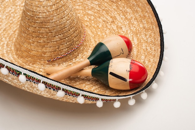 Close up view of wooden maracas on sombrero on white background