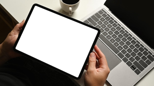 Крупный план работника, сидящего за белым офисным столом и использующего цифровой планшет Пустой экран для рекламного текста
