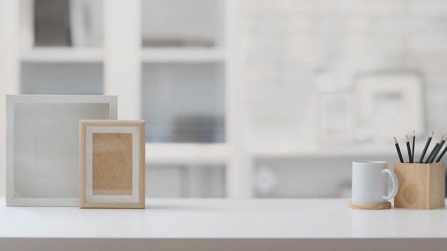Крупным планом вид на рабочем месте с копией пространства, рамки, карандаши и чашка кофе на белом столе