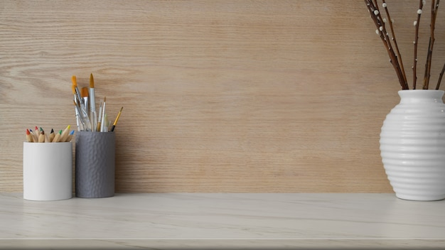 Close up view of workplace with copy space, painting tools and ceramic vase