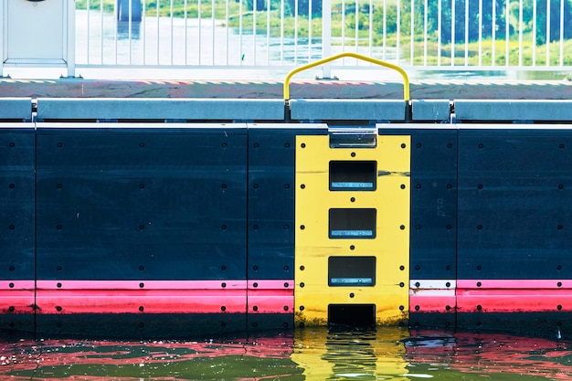 Photo close-up view of the yellow marked rescue ladder on the smooth high wall of an airlock