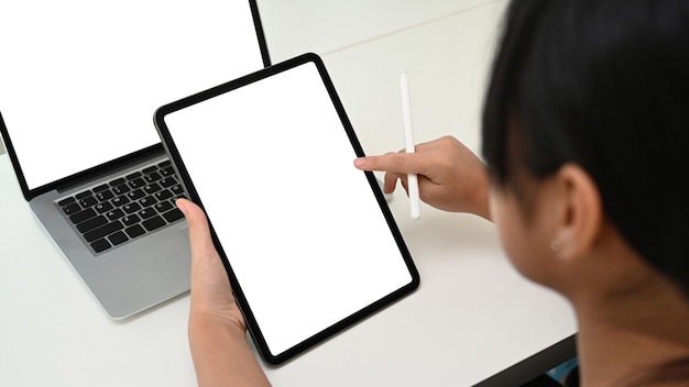 Close up view of young children woman studying online with computer laptop and using digital tablet at home.