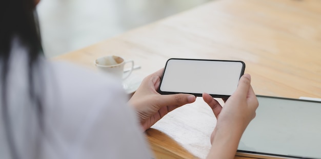 空白の画面のスマートフォンを見て若い女性医師のクローズアップビュー