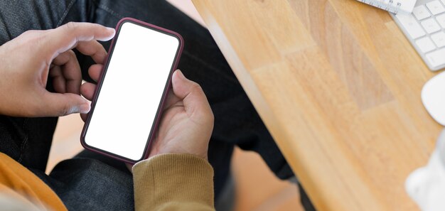 Close-up view of young man holding blank screen smartphone in comfortable office