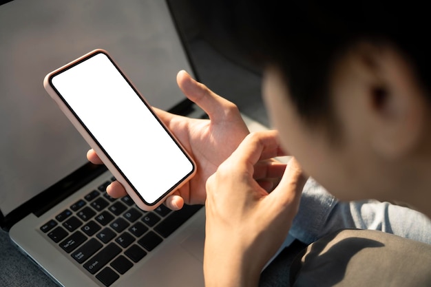 Close up view of young man lying on sofa with laptop computer and using smart phone
