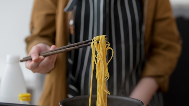 Foto chiuda sul punto di vista della giovane donna che cucina nella sua stanza della cucina