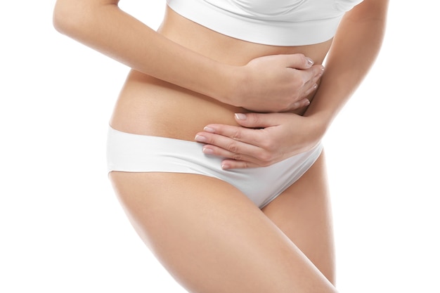 Close up view of young woman suffering from abdominal pain, on white. Gynecology concept