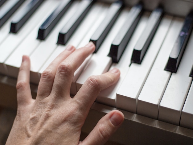 Close-up vingers van pianist op de pianotoetsen, armen speelt solo van muziek of nieuwe melodie. Handen van mannelijke muzikant spelen op synthesizer.