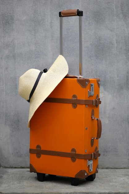 Close up of vintage style suitcase with summer hat on gray background for holiday concept