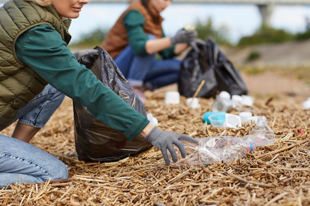 Close-up of volunteers cleaning the ground near the river in the nature