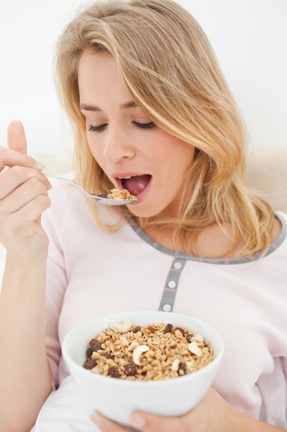 Close-up, vrouw die op het punt staat een lepel ontbijtgranen te eten, met een kom in haar andere hand