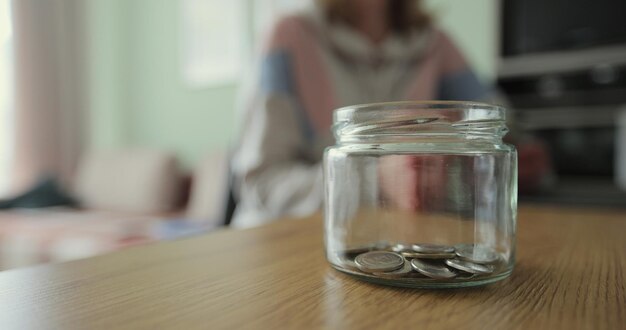 Close-up vrouw en man neemt dollars van de spaarpot Glazen pot met contant geld Het geld in de spaarpot Familie geld besparen