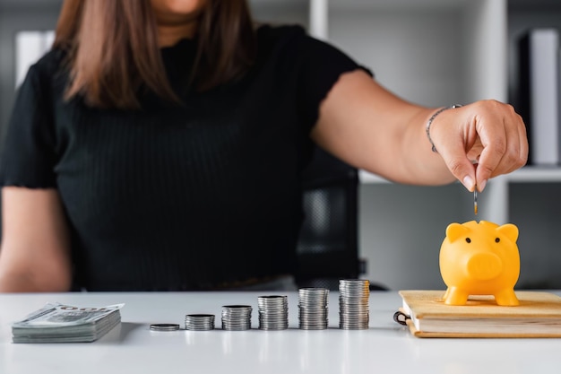 Close-up vrouw stopt munten in een spaarvarken met een stapel munten om geld te besparen