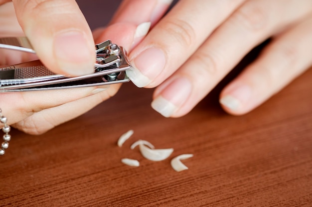 Foto close-up vrouw vingernagels worden bijgesneden met nagelknipper. het concept van zorg, schone vingernagels.