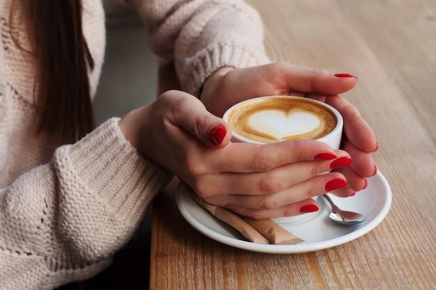 Close-up vrouwelijke handen die een kop met koffie houden
