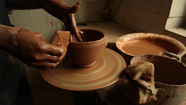 Close-up vrouwelijke handen die kleipot maken in een atelier Onbekende kunstenaar die beeldhouwwerk maakt van natte klei in een studio Onbekende vrouwelijke keramiekmaker die handgemaakt product in aardewerk maakt in slow motion