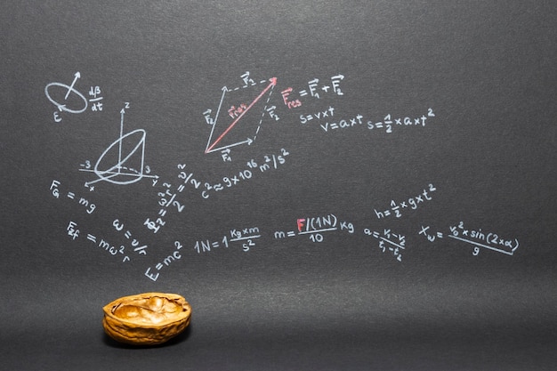 Close-up of walnut against formulas on blackboard