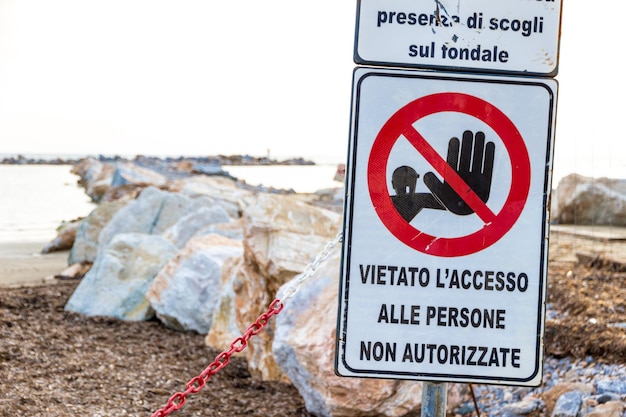 Photo close-up of warning sign on beach against sky