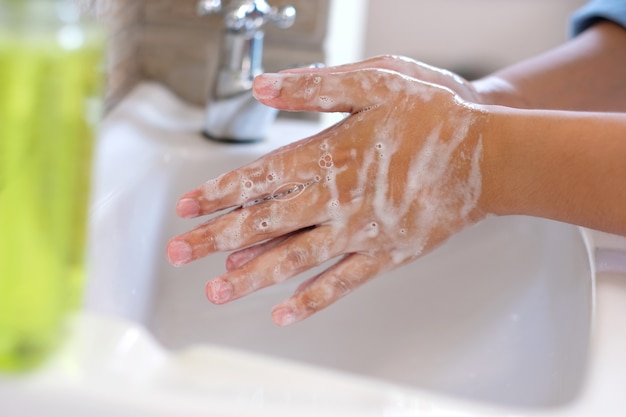 Chiuda in su delle mani di lavaggio che sfregano con il sapone