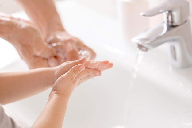 Foto close-up di lavaggio delle mani con sapone sul rubinetto durante la pandemia di covid-19