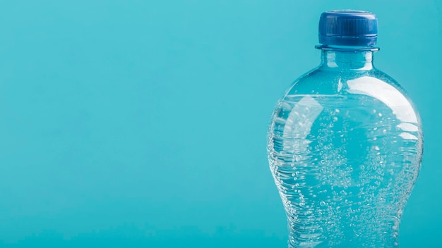 Близкий план бутылки с водой на синем фоне