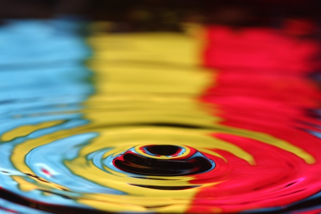 close up of a water drop falling and impact with a body of water