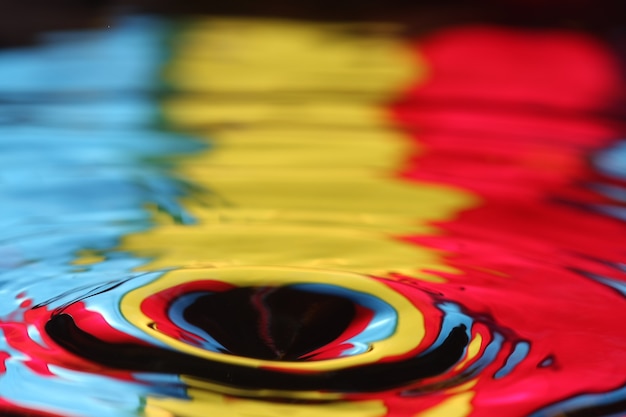 close up of a water drop falling and impact with a body of water