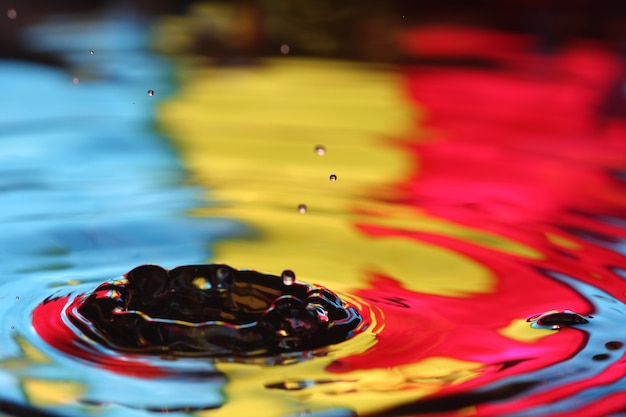 close up of a water drop falling and impact with a body of water