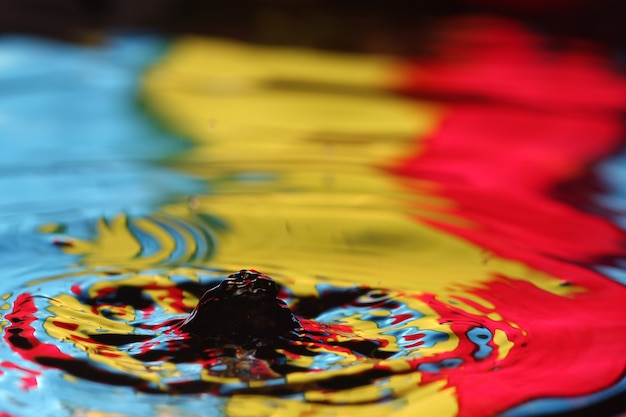 close up of a water drop falling and impact with a body of water