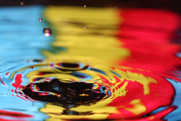 close up of a water drop falling and impact with a body of water