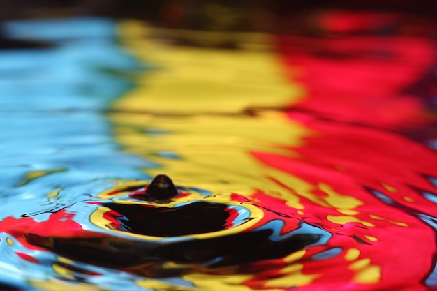 close up of a water drop falling and impact with a body of water