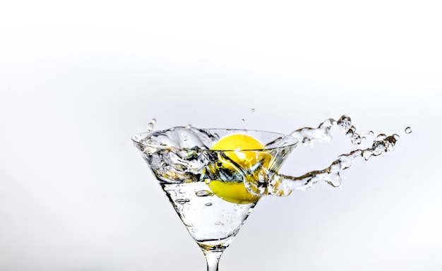 Close up of water drop falling into a glass on white background.