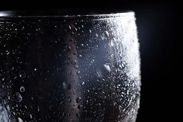 Foto chiudere le goccioline d'acqua su sfondo nero. gocce d'acqua su un bicchiere. luce su un vetro laterale.