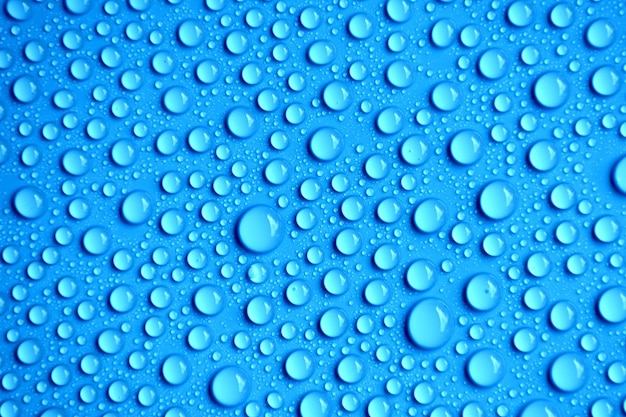 Foto close-up di gocce d'acqua su superficie blu