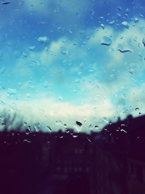 Foto close-up di gocce d'acqua su vetro contro sfondo di silhouette