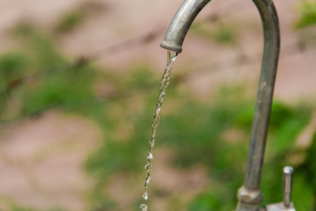 Photo close-up of water falling from faucet against blurred background