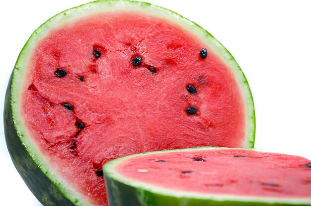 Close-up of a watermelon cut into two halves with black seeds on white