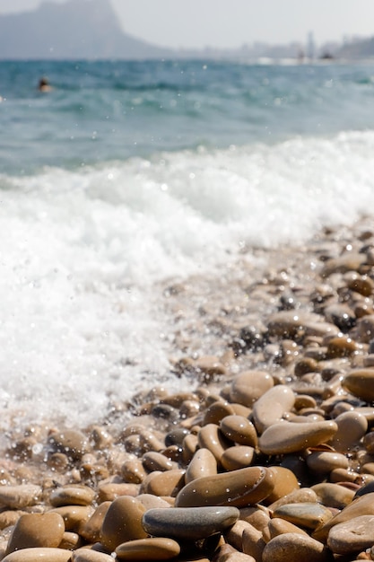 A close up of a wave crashing on a rocky beach.