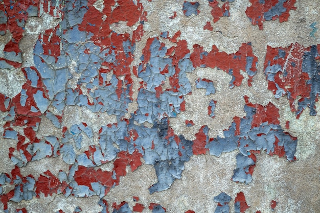 Close-up weathered wall with chipped blue and red paint. Old colored concrete wall. cracked texture