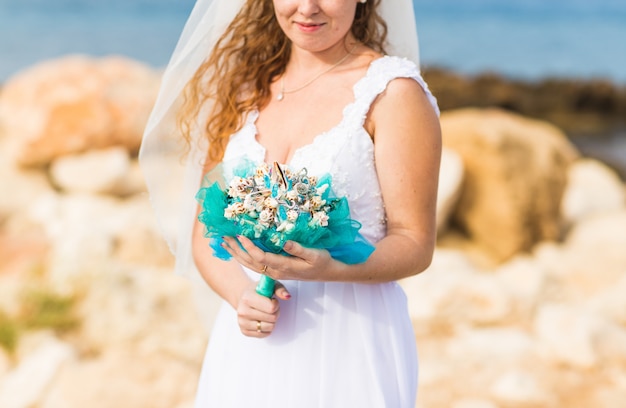 Close-up of wedding bouquet with seashells in hands of the bride.