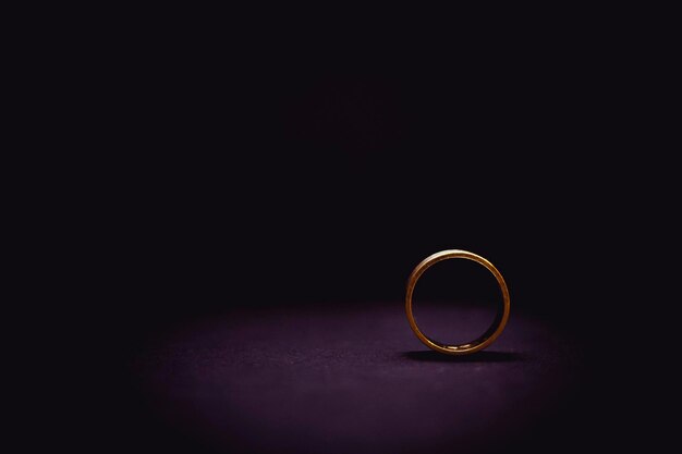 Photo close-up of wedding ring on table against black background