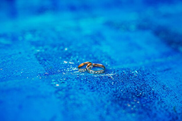 Close-up of wedding rings on blue surface